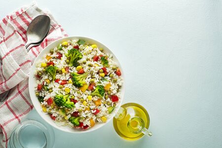 Fresh rice salad with mixed vegetables in a bowl on blue tableの写真素材