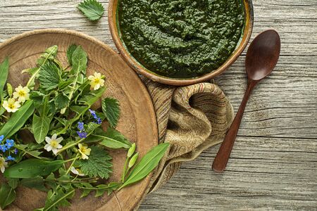 Healthy soup with fresh spring ingredients. Dandelion, wild garlic, flowers and nettle leaves on wooden backgroundの写真素材