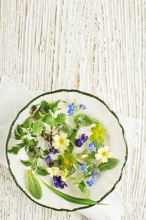 Healthy spring food ingredients. Dandelion, flowers, wild garlic and nettle on wooden backgroundの写真素材