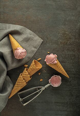 Fruit ice cream scoops, scooped in to waffle cones with a silver utensilの写真素材