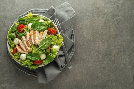 Healthy Chicken Green lettuce salad with tomato and mozzarella on grey table backgroundの写真素材