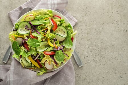 Green lettuce salad with fresh mixed vegetables on grey table backgroundの写真素材