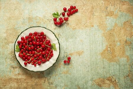 Fresh red currant berries with leaf in plate close upの写真素材