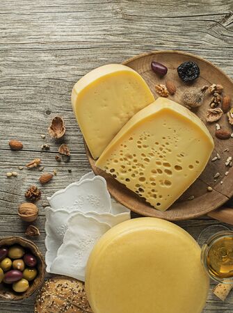 Assortment of cheeses, wine, nuts and fruits on a wooden table. Top view. Free space for text.の写真素材