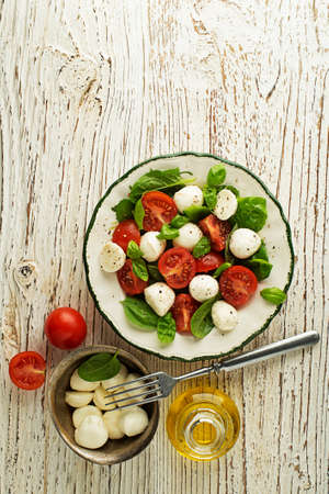 Delicious caprese salad with ripe tomatoes and mozzarella cheese with fresh basil leaves. Italian food.の写真素材