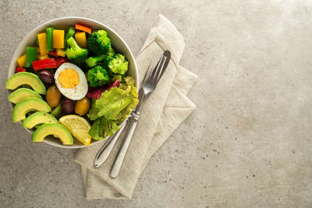 Healthy salad meal with egg, avocado and mixed fresh vegetables on grey background top view. Healthy meal conceptの写真素材
