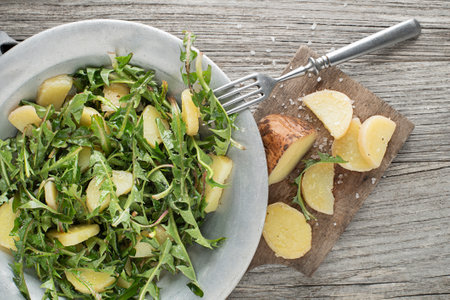 Healthy dandelion salad with potatoes on wooden background close upの写真素材