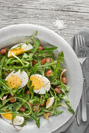 Fresh dandelion salad with beans and eggs on wooden backgroundの写真素材