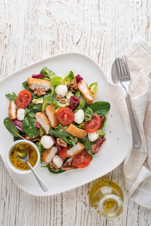 Healthy salad with crispy fried chicken breast strips, cheese and tomatoesの写真素材
