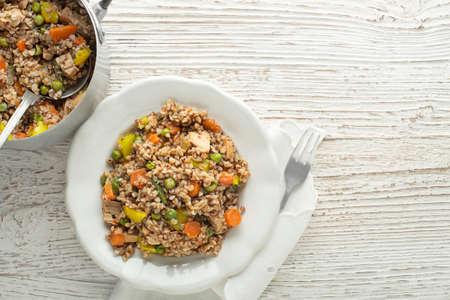 Buckwheat dish with chicken and vegetables served on plate on wooden tableの写真素材