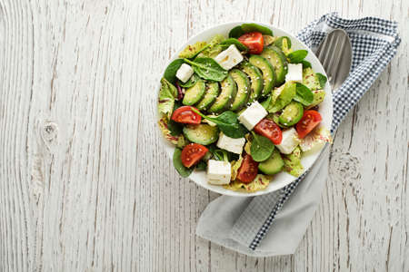 Healthy green salad with avocado and feta cheese on wooden tableの写真素材