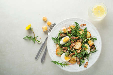 Dandelion salad with eggs potatoes bacon and croutons on grey backgroundの写真素材