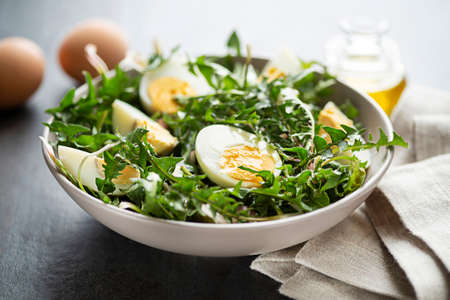 Healthy dandelion salad with eggs on grey background close upの写真素材