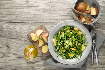 Healthy dandelion salad with potatoes on wooden background close upの写真素材