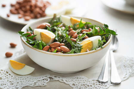 Healthy dandelion salad with beans and egg on white background close upの写真素材
