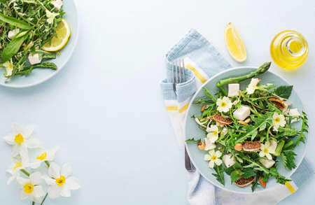 Spring salad with dandelion, asparagus, wild garlic, flowers, nettle and cream cheese. Healthy spring detox food background.の写真素材