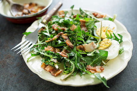 Dandelion salad with eggs and roasted bacon close upの写真素材