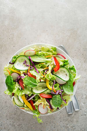 Green lettuce salad with fresh mixed vegetables on grey table backgroundの写真素材
