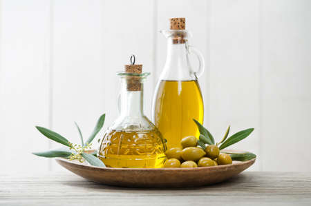 Olive oil bottles with green olives fruit and olive branch on wooden tableの写真素材