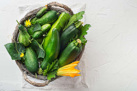 Basket of fresh vegetable crops with zucchini and cucumber on white backgroundの写真素材