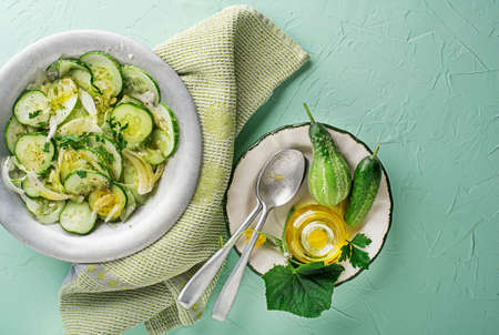 Cucumber salad. Preparation of fresh cucumber salad on green backgroundの写真素材