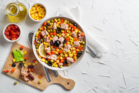 Healthy tuna salad with corns, carrots, peas, peppers and olives on white table background. Mexican corn salad.の写真素材