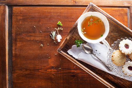 Tea Cup with of fresh herbal leaves and cookies on wooden background, top view, place for text. Healthy conceptの写真素材