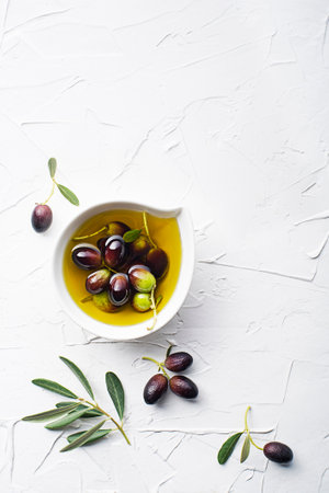 Olive oil in bowl with fresh olives fruit and olive branch on white backgroundの写真素材