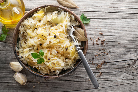 Homemade sauerkraut with black pepper and parsley in wooden bowl on rustic background. Top view. Copy space.の写真素材