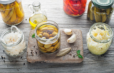 Canned and pickled vegetables in glass jars on wooden table. Preserved foodの写真素材