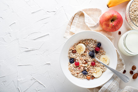 A bowl of dry granola and muesli served with fresh fruit and nuts. Oatmeal plate. Healthy food, diet. Top view.の写真素材