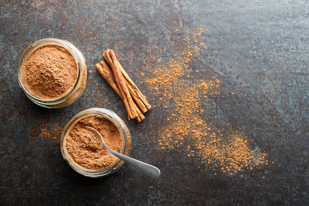 Ground cinnamon in glass cups and cinnamon sticks with powder on grey rustic backgroundの写真素材