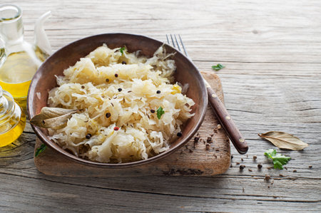 Homemade sauerkraut with black pepper and parsley in bowl on rustic background. Copy space.の写真素材