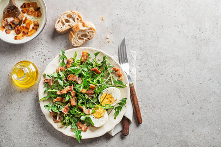Dandelion salad with egg and roasted bacon on plateの写真素材
