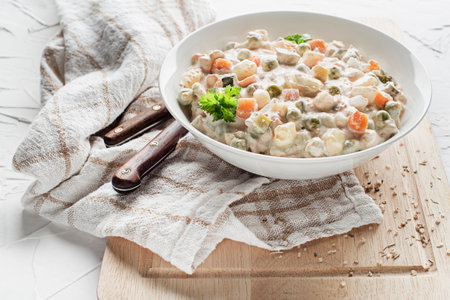 Bowl of russian salad olivier french salad with vegetables and egg dressed with mayonnaise on white table close upの写真素材