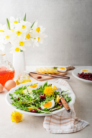 Dandelion salad with eggs, potato and beans on bright table backgroundの写真素材