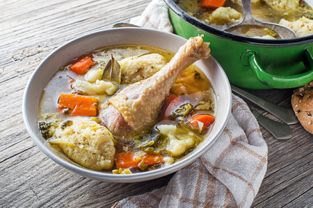 Fresh chicken soup with vegetable and semolina dumplings on wooden table close upの写真素材