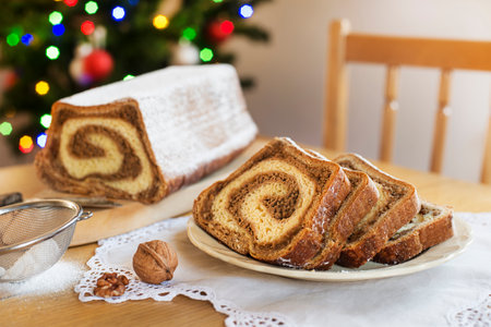 Christmas holidays celebration dessert. Potica, traditional Slovenian bread cake roll in front of christmas treeの写真素材