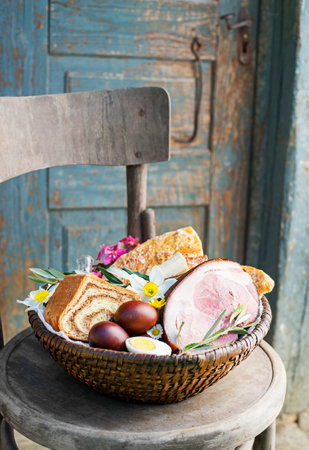 Easter traditional food with ham, eggs and bread in basket. Holidays background. Easter basket filled with all sorts of delicious delicatessenの写真素材