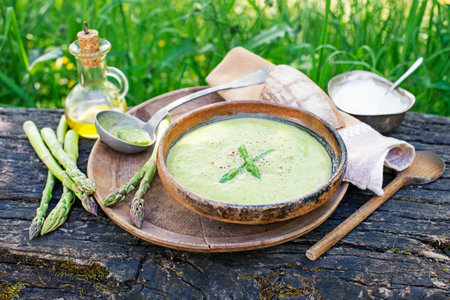 Fresh Asparagus creamy soup on wooden table outside in the gardenの写真素材