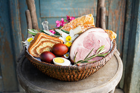 Easter traditional food with ham, eggs and bread in basket. Holidays background. Easter basket filled with all sorts of delicious delicatessenの写真素材