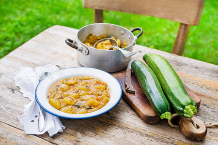 Eating Slovenian traditional dish with zucchini sauce in red. Freshly picked zucchini from the garden. Summer foodの写真素材