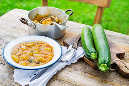 Eating Slovenian traditional dish with zucchini sauce in red. Freshly picked zucchini from the garden. Summer foodの写真素材