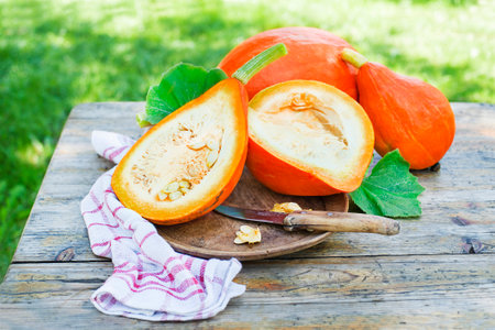 Cutting hokkaido pumpkin or red kuri squash with knife close up. Outdoors in the gardenの写真素材