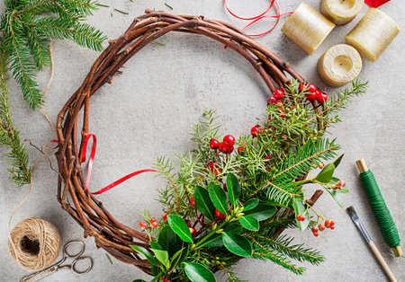 Making Advent wreath from natural branches of spruce, juniper and holly red berries. Decorations for christmas wreath at homeの写真素材