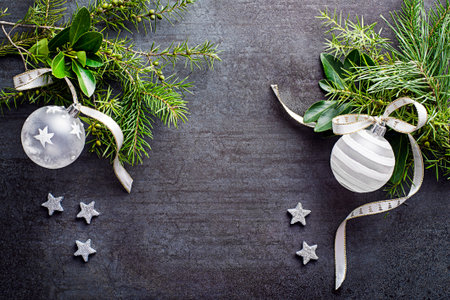 Christmas background. Natural branches with white baubles, ribbon bow and shiny stars on dark grey backdrop.の写真素材