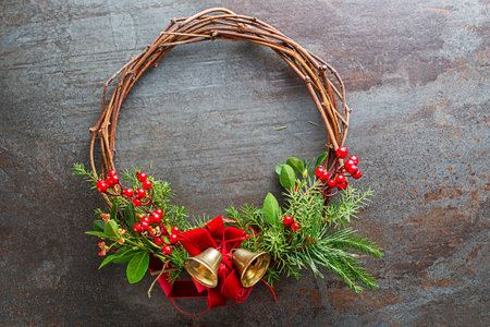 Christmas wreath from natural branches, holly red berries decorated with red bow and golden bell.の写真素材