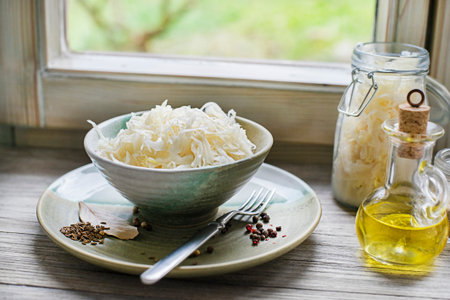 Homemade sauerkraut with black pepper and cumin seeds on wooden background.の写真素材