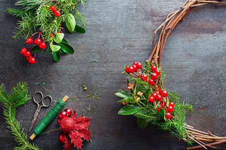 Making Christmas wreath from natural branches of spruce, juniper and holly red berries. Decorations for christmas wreath at homeの写真素材