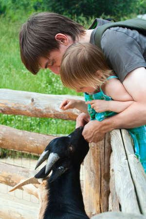 Father and daughter together feeding goat kid.の写真素材